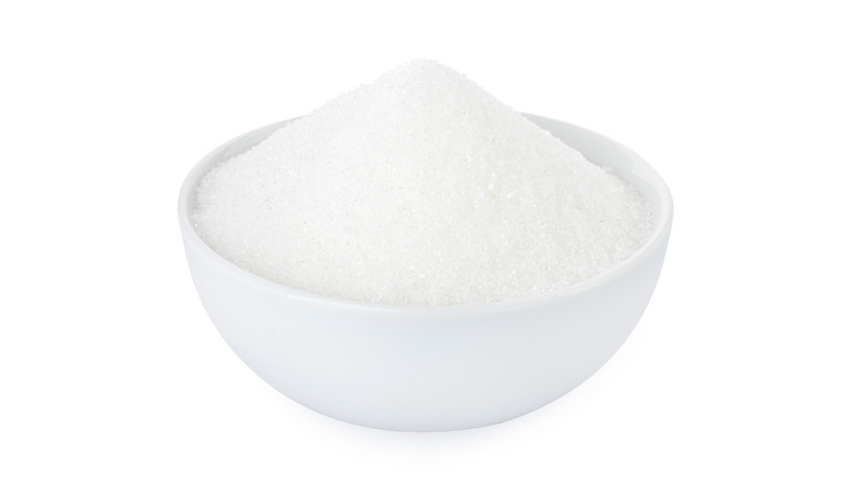 Granulated sugar in while bowl with white background