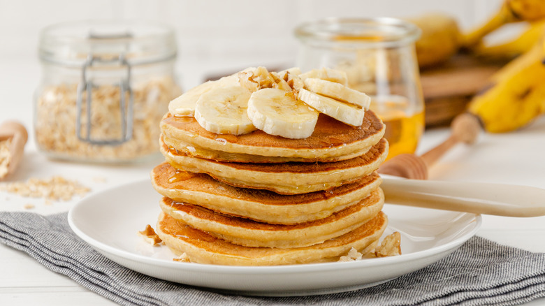 Banana pancake stack on plate with honey and walnuts