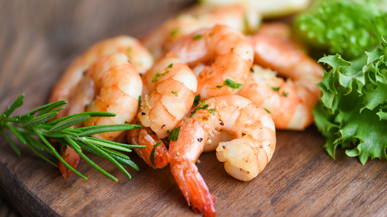 Shrimp with lettuce and rosemary on wood board