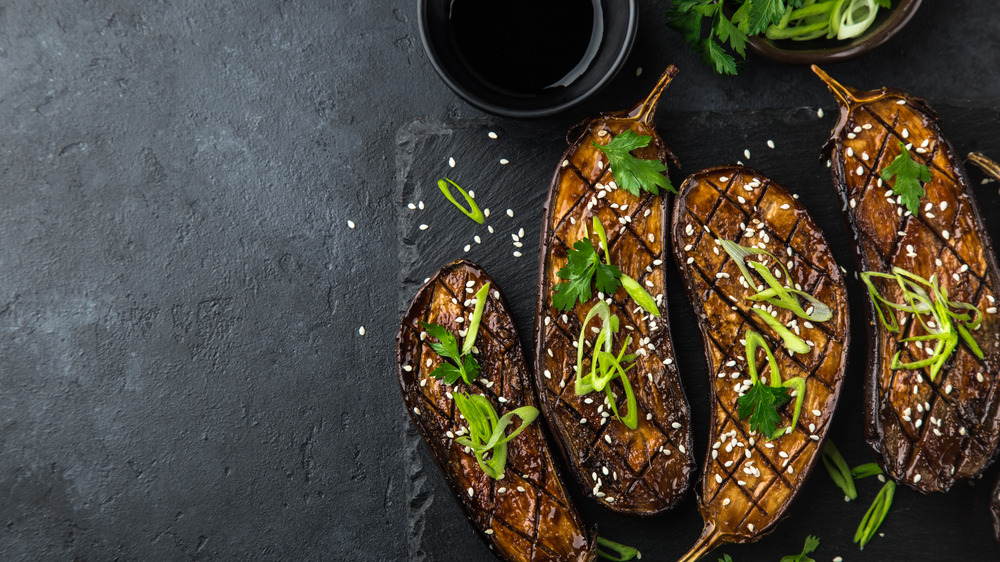 Grilled eggplants and scallions on a black background