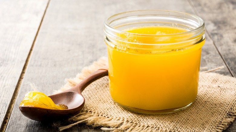 clear jar of ghee with wooden spoon