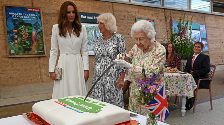 Queen Elizabeth II cutting cake with sword