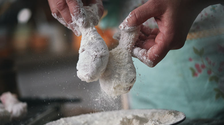 person breading chicken