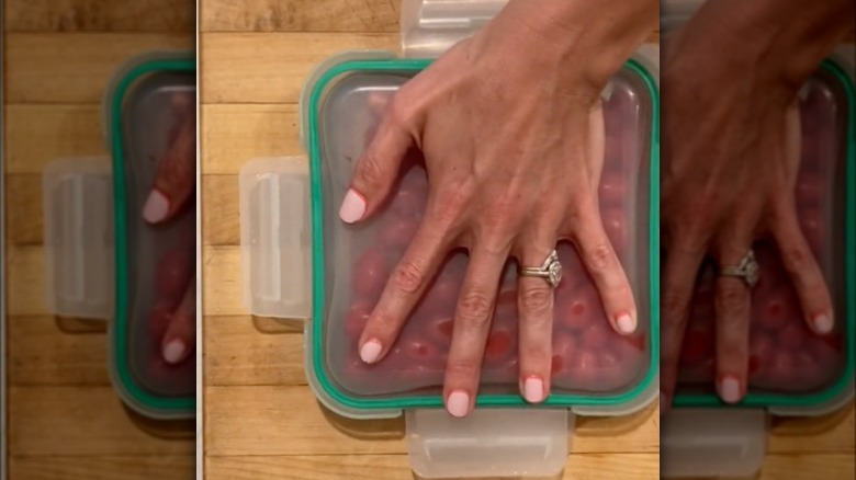 Person using lids to slice grape tomatoes faster