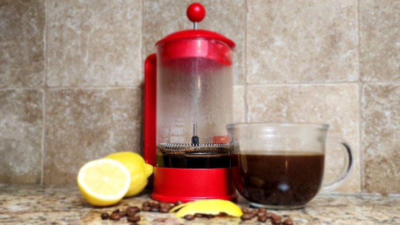 French press with lemon coffee and coffee beans