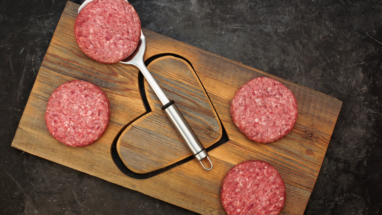 Burger patties on heart cutting board