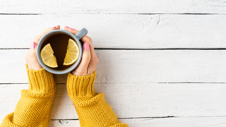 Holding mug of liquid with lemon