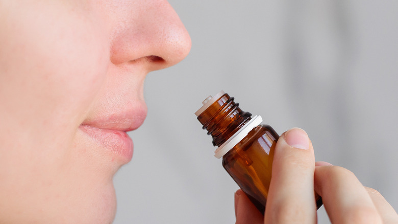 A person holding a brown vile near their nose