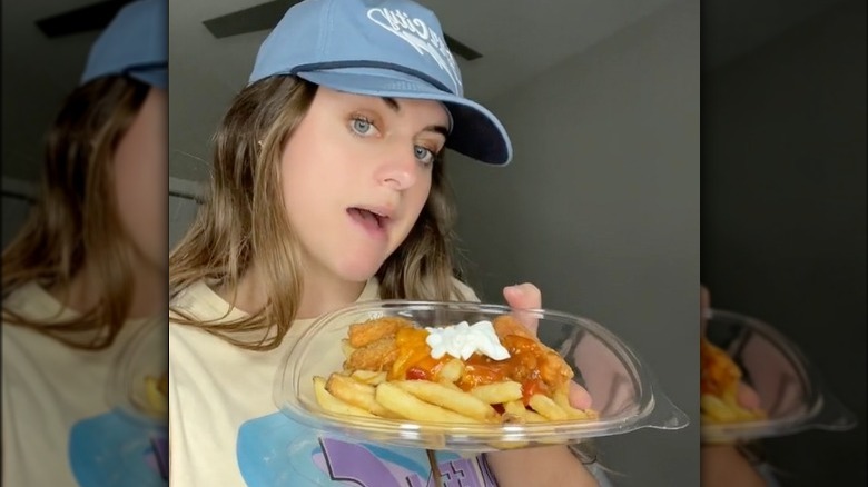 Girl holding Wendy's fries with chili, nuggets, sour cream