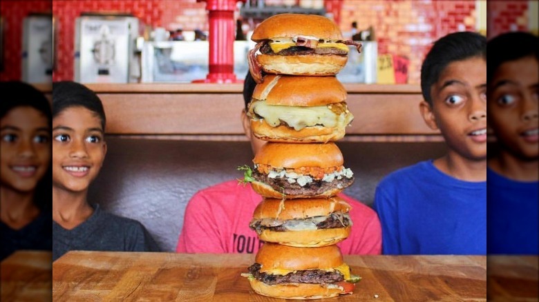 children staring at stacked burgers