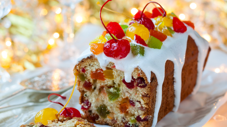 Sliced fruitcake topped with glazed fruit and icing