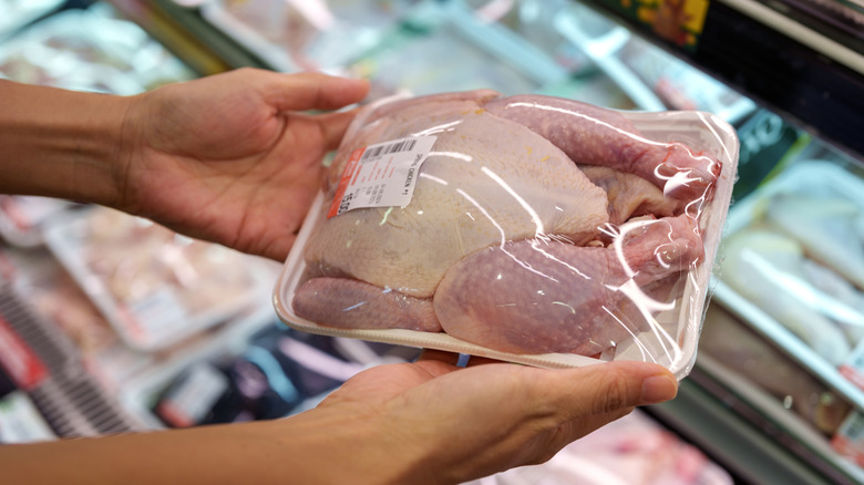 Person shopping for raw chicken at supermarket