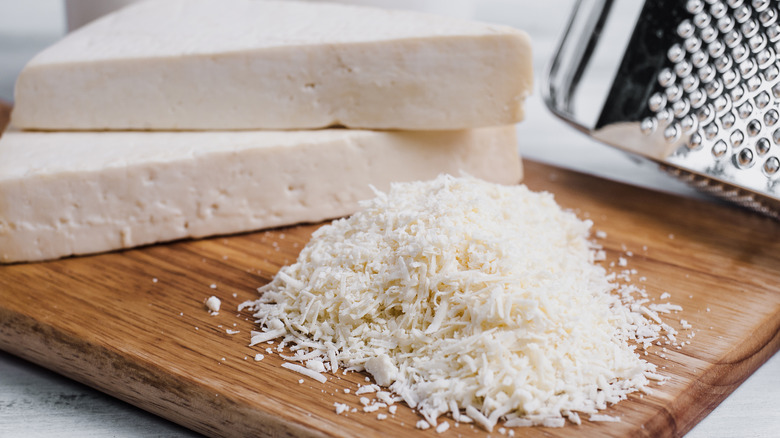 Fresh grated cotija cheese on cutting board