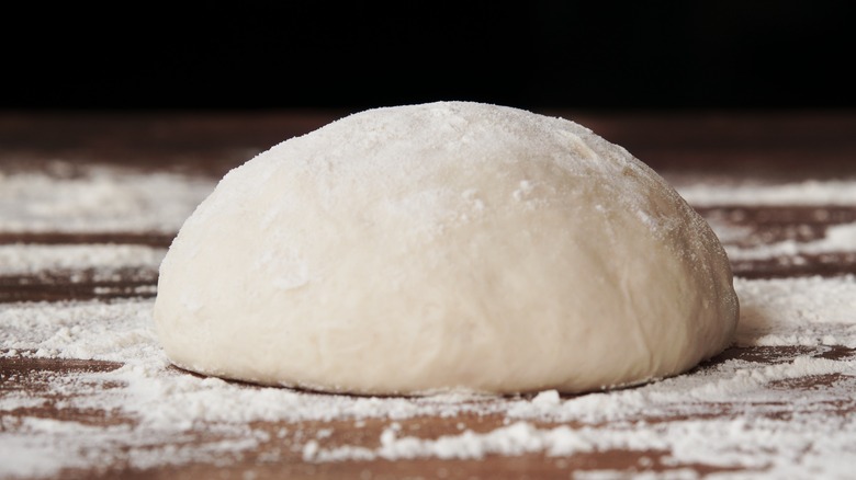 pizza dough on a floured wooden surface