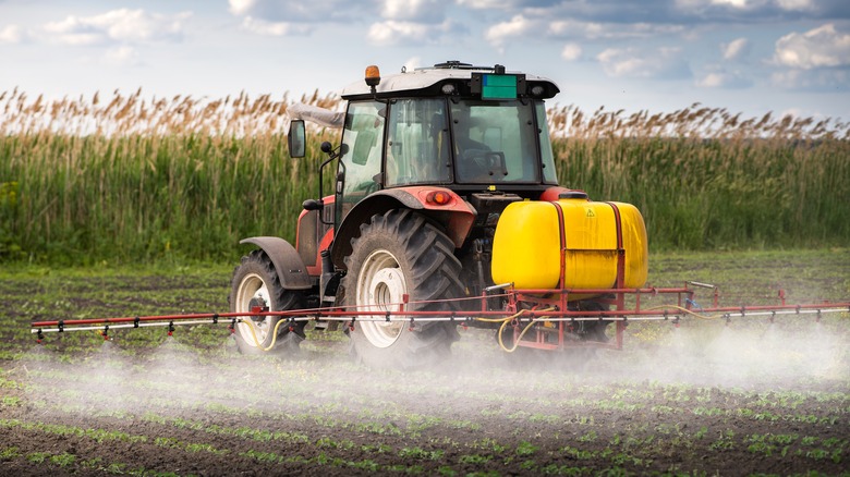 Tractor spraying pesticides in field