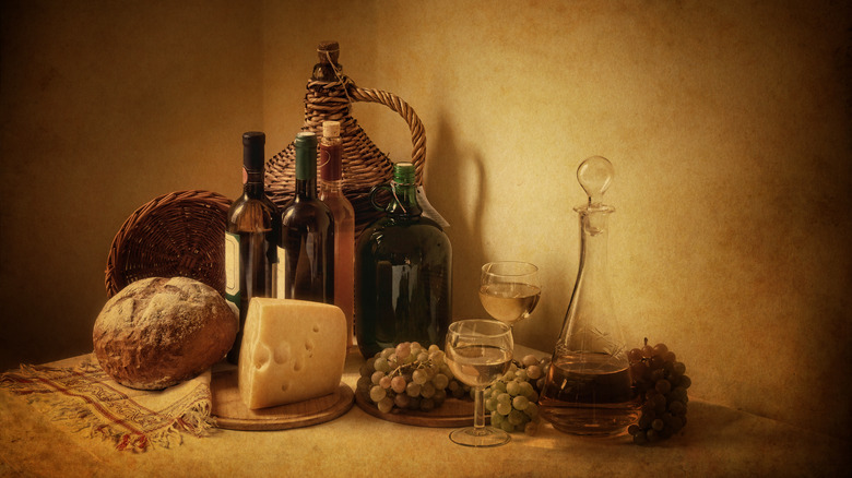 Cheese, wine, bread, a decanter and baskets 