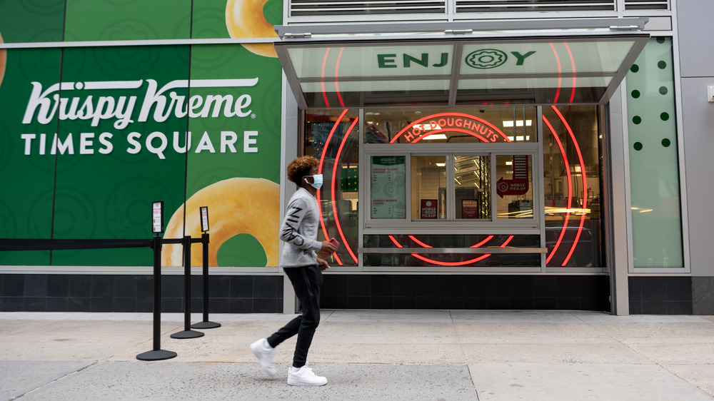 A person in a mask walking past Krispy Kreme