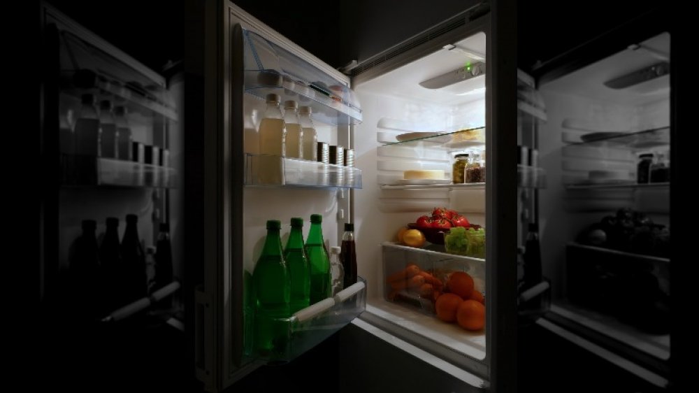 An open domestic refrigerator with food and drink at night