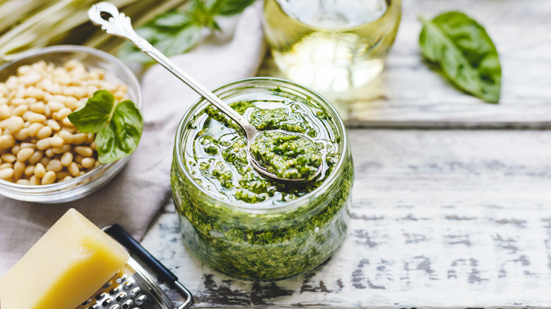 Jar of pesto surrounded by pesto ingredients