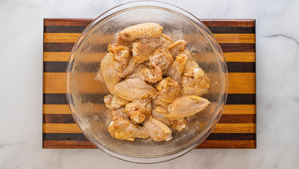 chicken wings being seasoned