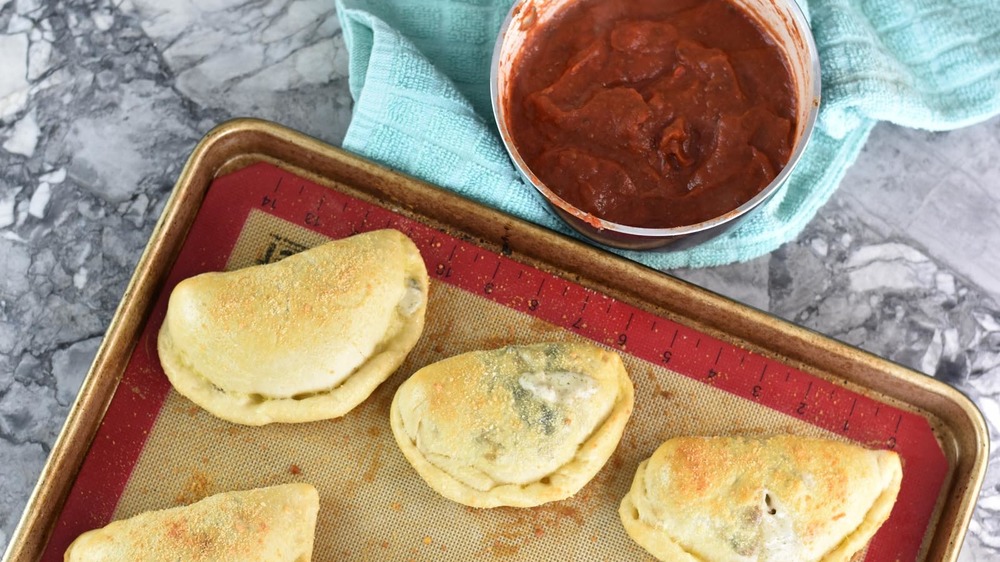 Calzones on a pan with dipping sauce