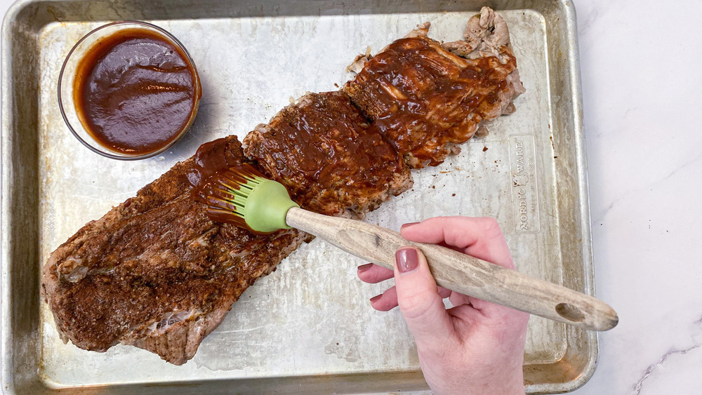 Applying barbecue sauce to ribs