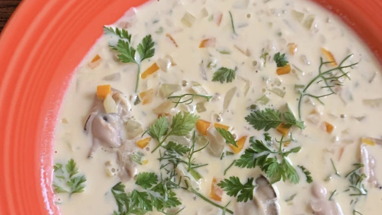 Oyster stew with herbs in red bowl