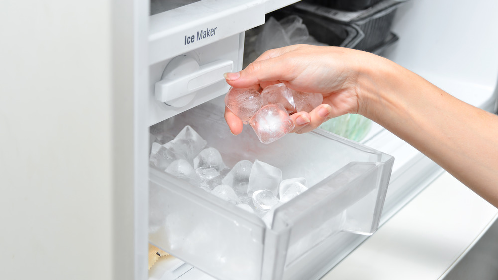 Hand picking ice cubes out of a plastic ice cube tray