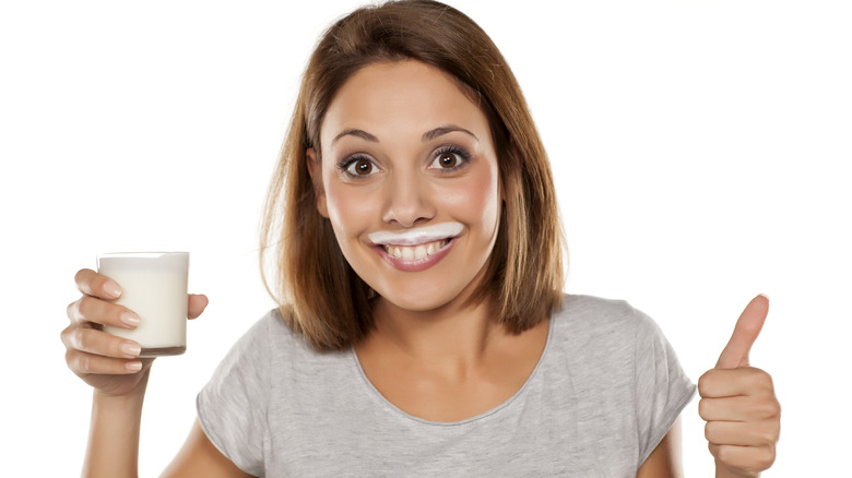 woman giving thumbs up holding milk