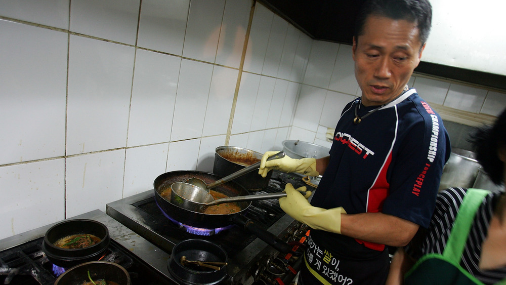 Korean chef standing in front of stove