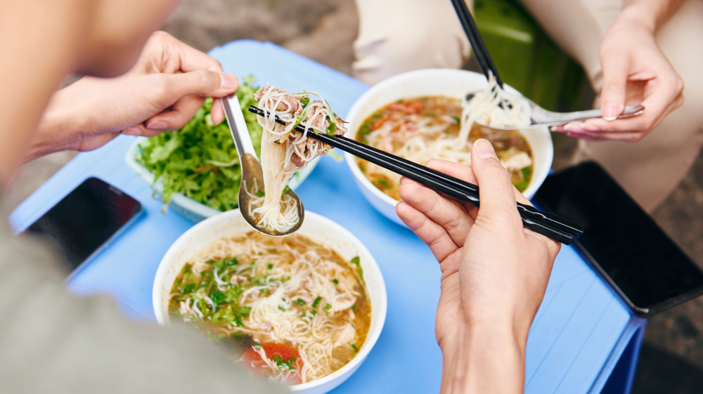 Eating pho in white bowls on blue table