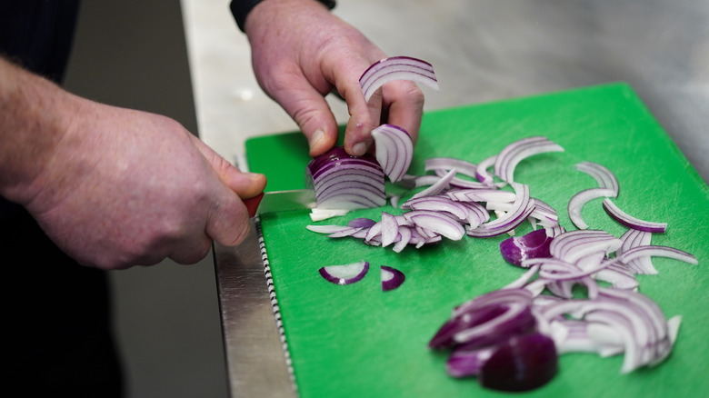 person chopping onions in a restaurant