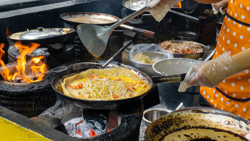 Person cooking vietnamese pancakes in a pan