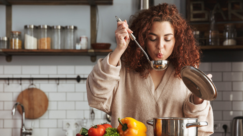 woman tasting soup from ladle