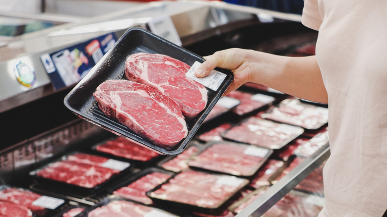 person buying meat at grocery store