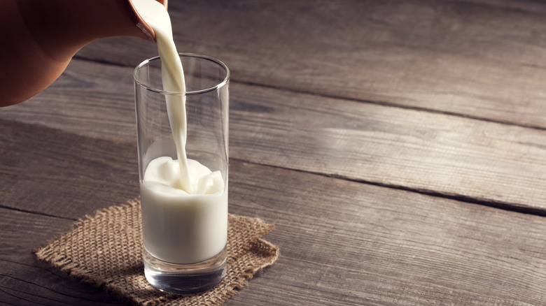 milk being poured into glass on wooden table