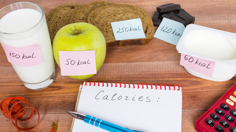 Different foods with calorie labels on table