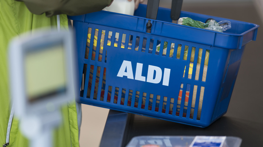 A customer holding a shopping cart at Aldi