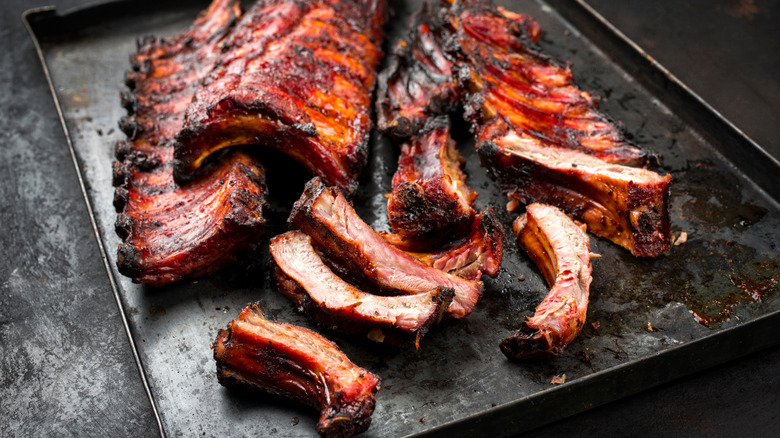 Slab of barbecue ribs on metal try with pieces broken off