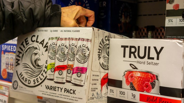 consumer taking White Claw case off shelf next to Truly box