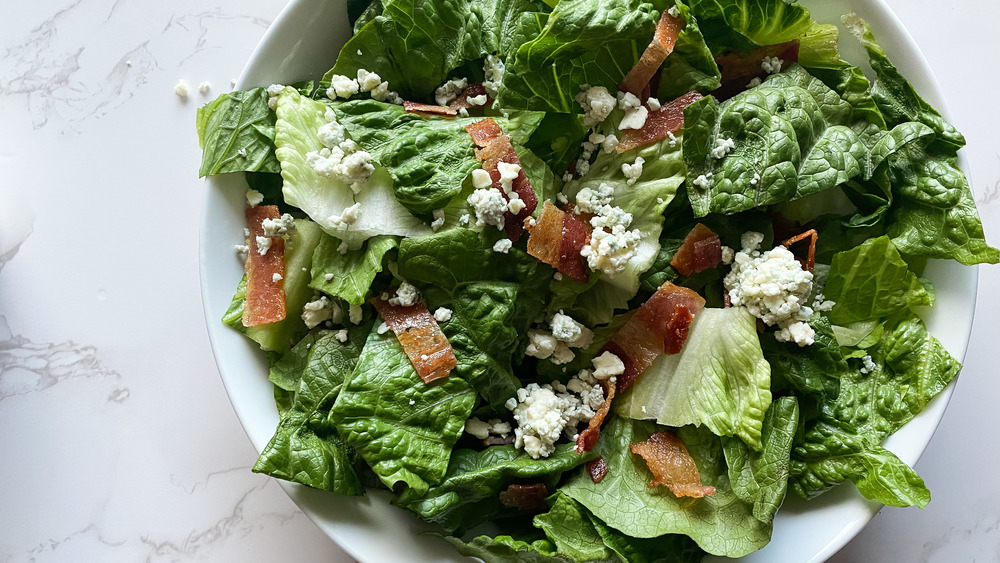 sliced bacon and blue cheese on romaine lettuce in bowls