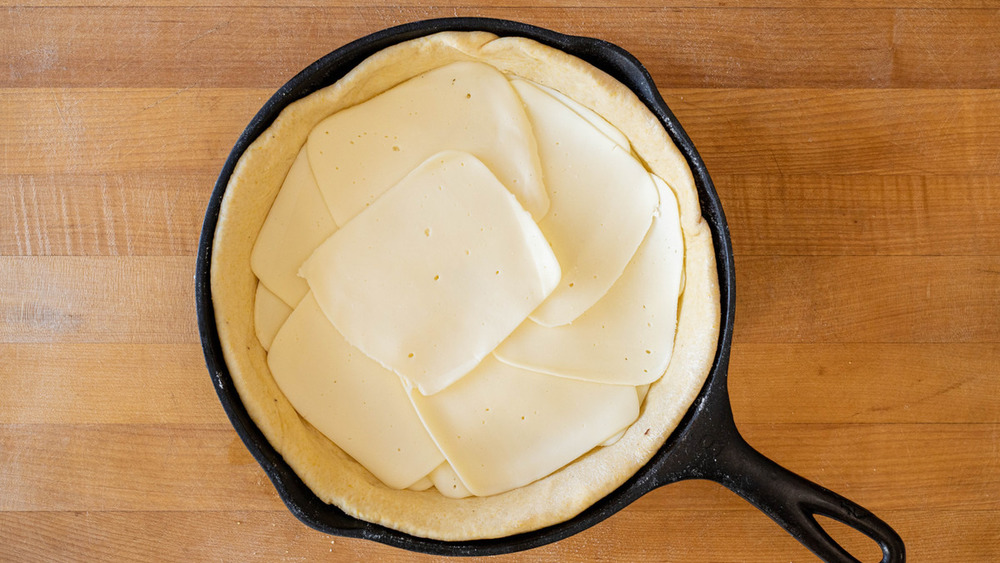 cheese layered on top of pizza dough for deep dish pizza recipe