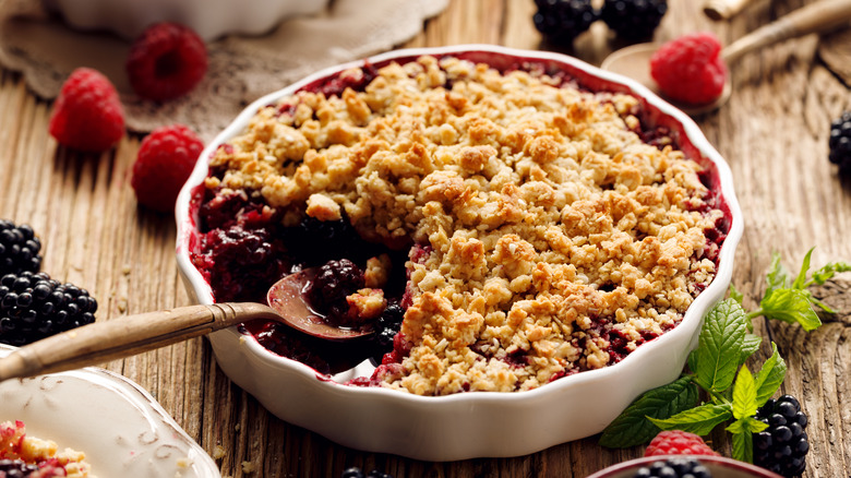 Mixed berry crumble in ramekin with wooden spoon