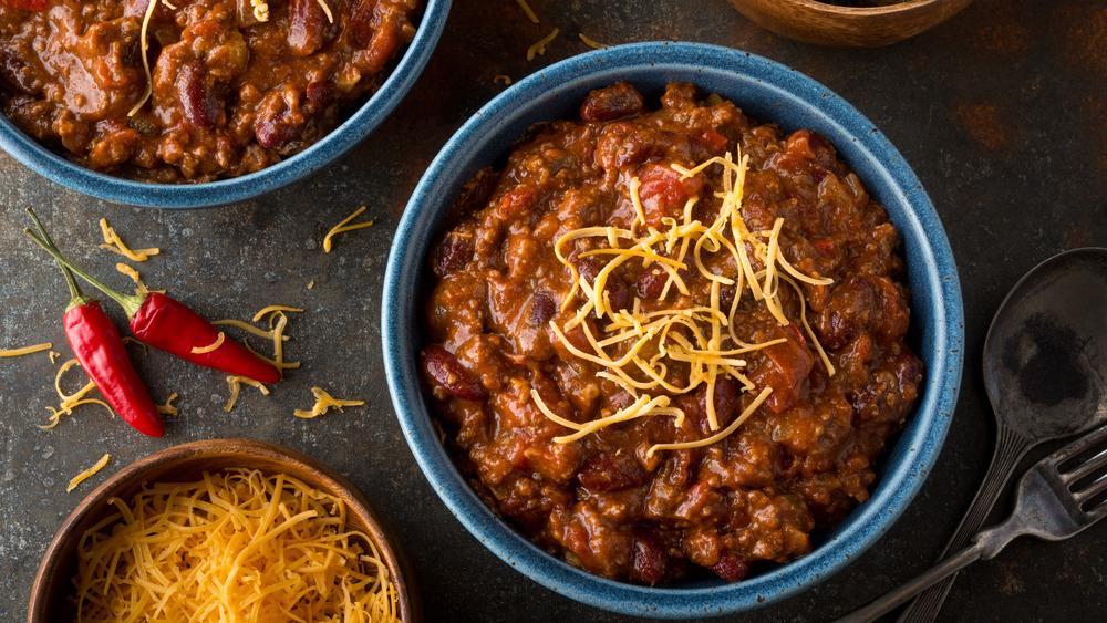 Bowls of chili with shredded cheese and chili peppers