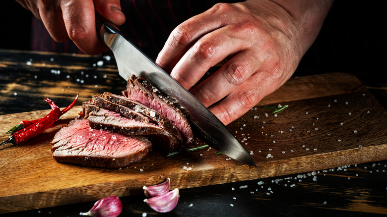 Hands using a knife to cut meat  