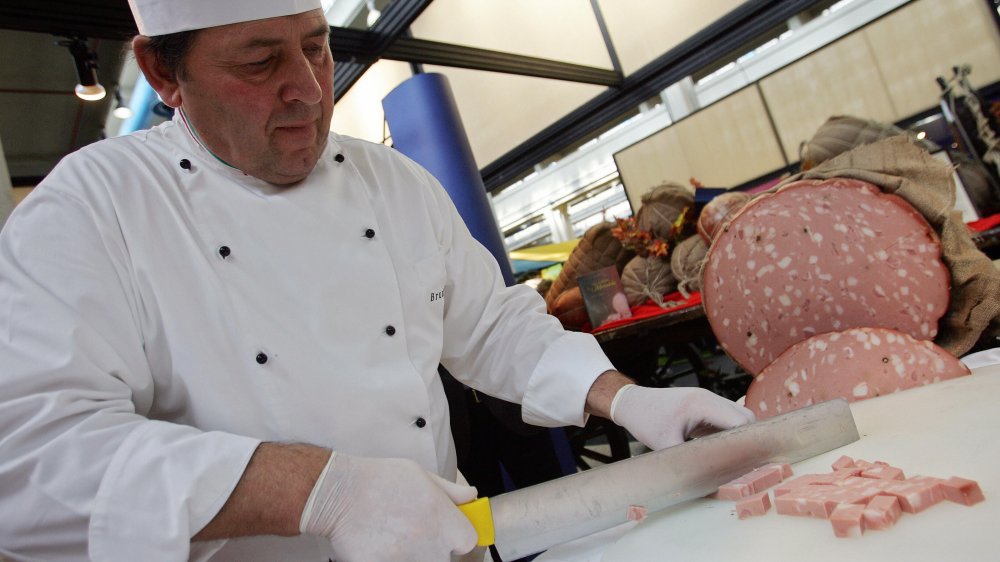 A chef chops some mortadella