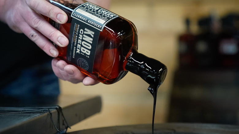 person dipping bourbon bottle in wax