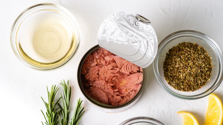 open canned tuna surrounded by spices, herbs and condiments