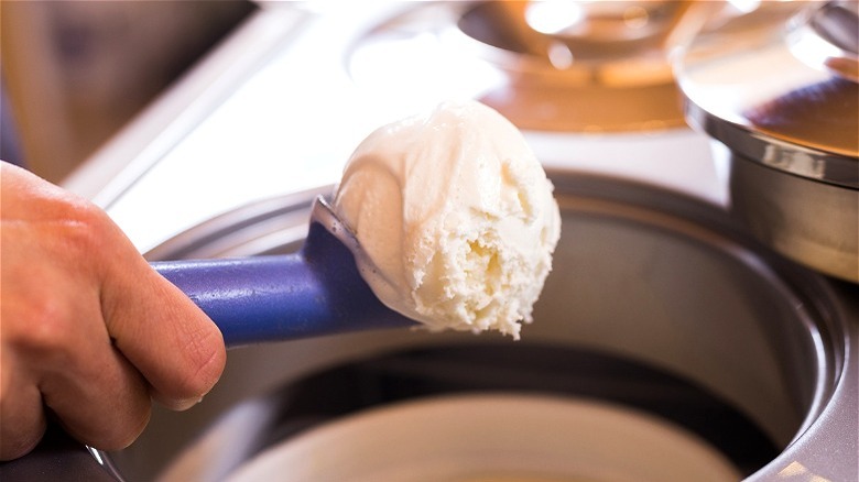 Vanilla ice cream in scooper over bowl