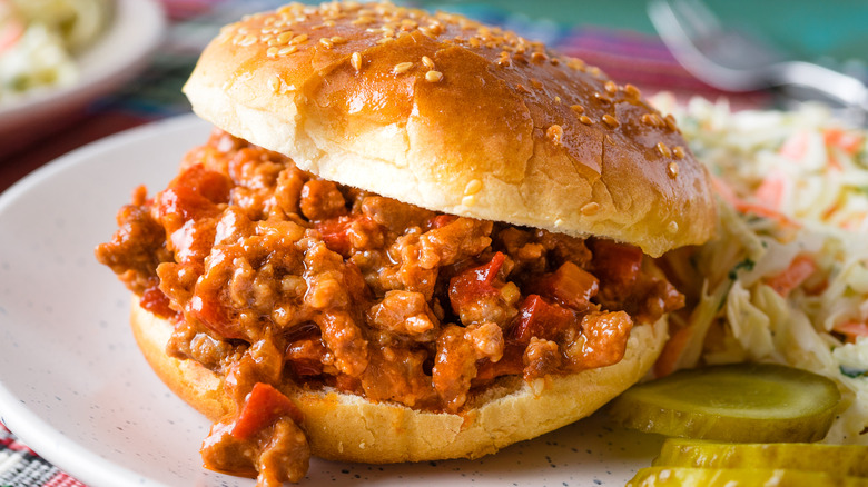 Sloppy Joe sandwich on plate with coleslaw and pickles